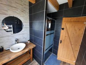 a bathroom with a sink and a wooden door at Gîte Les sepneilles ! in Gérardmer