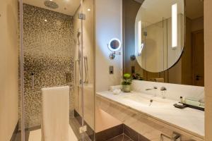 un bagno con lavandino, doccia e specchio di Embassy Suites By Hilton Doha Old Town a Doha