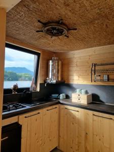 a kitchen with wooden cabinets and a window and a stove at AQUACHILL houseboat & wellness in Liptovský Trnovec
