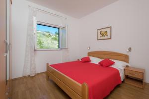 a bedroom with a red bed and a window at Apartments Plazibat in Hvar