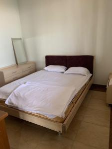 un letto con lenzuola e cuscini bianchi in una camera da letto di Home Martiros a Vagharshapat