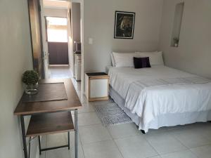 um quarto com uma cama e uma mesa em The Terrace Guest House em Roodepoort