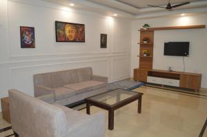 uma sala de estar com um sofá e uma televisão em Aarya Rishikesh - Luxurious 2 BHK em Rishikesh