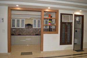 una cocina con armarios blancos y una puerta corredera de cristal en Aarya Rishikesh - Luxurious 2 BHK, en Rishīkesh
