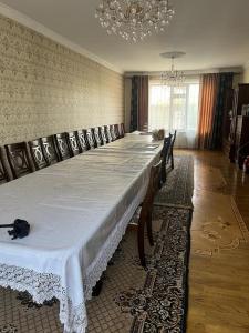 Уютная вилла в центре Бишкека في بيشكيك: طاولة طويلة مع كراسي في الغرفة