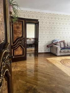 uma sala de estar com uma cama e um piso de madeira em Уютная вилла в центре Бишкека em Bishkek