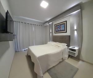 een slaapkamer met een wit bed en een televisie bij Santa House no Centro in Santa Cruz do Sul