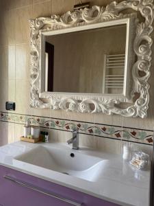 La salle de bains est pourvue d'un lavabo blanc et d'un miroir. dans l'établissement Appartamento tra verde e città, à Bologne