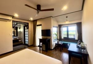 a bedroom with a bed and a desk with a ceiling fan at The Quin Riverside Villa in Hoi An