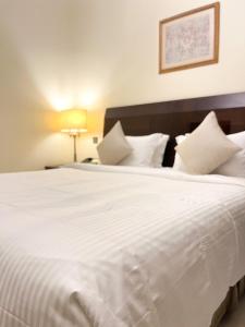 Elle comprend un grand lit blanc avec des draps et des oreillers blancs. dans l'établissement Al Gosaibi Hotel-Villa, à Khobar