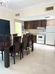 uma cozinha com uma mesa e cadeiras e um frigorífico branco em Al Gosaibi Hotel-Villa em Al Khobar