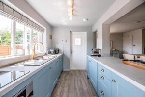 a large kitchen with blue cabinets and a window at Wonderful cottage with sun-filled terrace in Aldringham