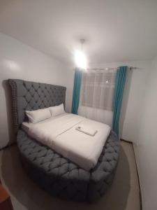 Una cama en una habitación con una luz sobre ella en Jacky's Milimani suites en Nakuru