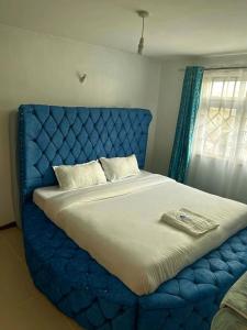 a large bed with a blue headboard in a bedroom at Jacky's Milimani suites in Nakuru