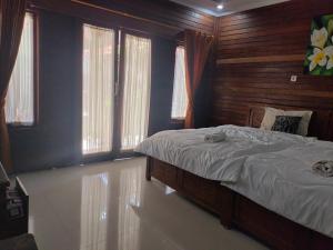 een slaapkamer met een groot bed met houten wanden en ramen bij PENIDA MEMORIES COTTAGE in Batununggul