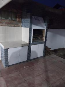 a kitchen with white cabinets and a brick wall at Tu Casita de Paso in General Acha