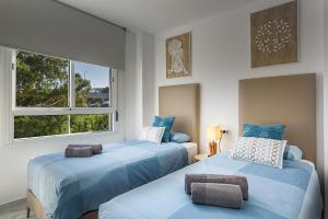 two beds in a room with two windows at Relax at Premium Beach flat - Aldea Beach in Manilva