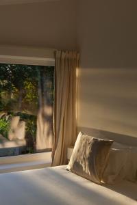 uma cama com uma almofada em frente a uma janela em A Padaria Farmhouse em Cinfães