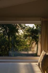a window in a bedroom with a view of trees at A Padaria Farmhouse in Cinfães