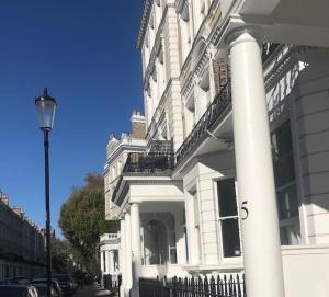 een wit gebouw met een hek ervoor bij South Ken designer pad in Londen