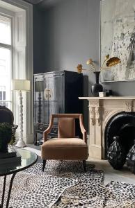 ein Wohnzimmer mit einem Stuhl und einem Kamin in der Unterkunft South Ken designer pad in London