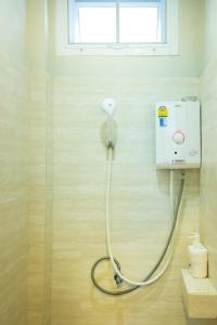 Dorm of Happiness by Tharaburi Resort في سوخوثاي: دش في حمام مع خرطوم معلق على الجدار