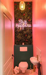 a pink bathroom with a toilet and a sign on the wall at Anouste Lou Bercail - cocon entièrement rénové avec vue sur la montagne in Campan