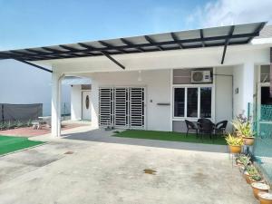 een wit huis met een patio met stoelen en tafels bij Malay Homestay di Meru, Klang in Kapar