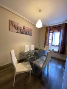 comedor con mesa de cristal y sillas blancas en Vivienda Turística en el casco antiguo VUT-LE- 566 Corazón del Barrio Húmedo en León