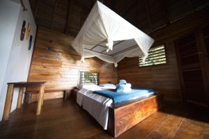 - une chambre avec un lit dans une pièce dotée de murs en bois dans l'établissement Nosy Komba Lodge, à Nosy Komba