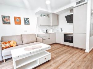 a white living room with a couch and a kitchen at Apartamento TIENDAS 8 in Almería