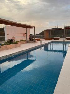 a swimming pool with blue water in front of a building at Apartasuite moderno y elegante en Playa Salguero in Gaira