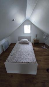 een wit bed in een zolderkamer met een raam bij Petite maison avec jardin DISNEYLAND PARIS in Saint-Augustin