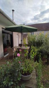 een patio met een tafel en een groene parasol bij Petite maison avec jardin DISNEYLAND PARIS in Saint-Augustin