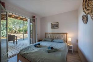 ラ・テスト・ド・ビュシュにあるPyla Villa DE LA DUNE promo vacances d'étéのベッドルーム1室(ベッド1台付)、スライド式ガラスドアが備わります。