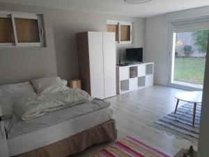 Schlafzimmer mit einem Bett, einem Tisch und einem Fenster in der Unterkunft Appartement au rez-de-chaussée d'une maison in Pessac