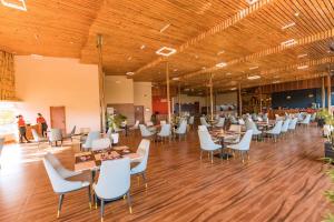 a dining hall with tables and white chairs at The Hut Restaurant & Boutique Hotel in Kigali