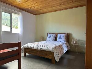 Schlafzimmer mit einem Bett und einem Fenster in der Unterkunft L'écho de la montagne in Cilaos