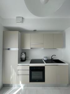 a kitchen with white cabinets and a black appliance at Crystal in Santo Stefano al Mare