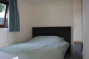 um quarto com uma cama com uma cabeceira preta e uma janela em Veluwe chalet em Putten