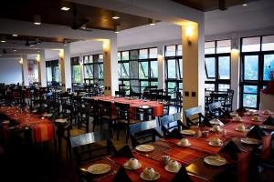 uma sala de jantar com mesas, cadeiras e janelas em Hotel Hill Top em Kandy