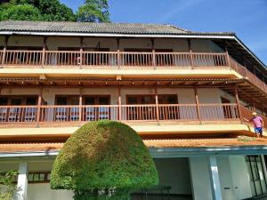 uma casa grande com uma árvore em frente em Hotel Hill Top em Kandy