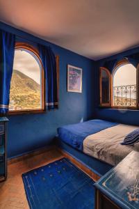 a bedroom with blue walls and two windows and a bed at Dar Zambra in Chefchaouene