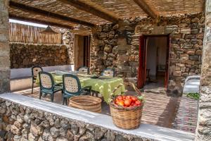 een patio met een tafel en stoelen en een mand met tomaten bij Dammuso i Pini di Kaddiuggia (CIR19081014C224053) & Dammuso di Mena (CIR 19081014C224052 in Pantelleria