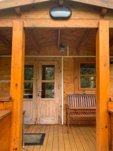 uma cabina de madeira com um banco num alpendre em Songbird Lodge - Near brew pub/10 mins from Snowdon em Caernarfon