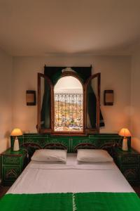 a bedroom with a green and white bed with a window at Dar Zambra in Chefchaouen