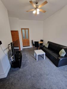 a living room with a black couch and a tv at Luna Apartments Newcastle Gateshead 3 in Gateshead