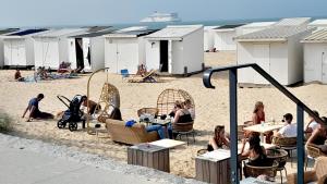 un groupe de personnes assises à des tables sur la plage dans l'établissement Studio plage, vue mer et dragon, garage pour moto, à Calais