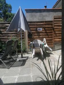 a patio with two chairs and an umbrella at Chambres dans maison familiale in Saint-Girons