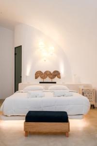 a white bedroom with a large white bed with a bench at Three Bells Suites in Firostefani